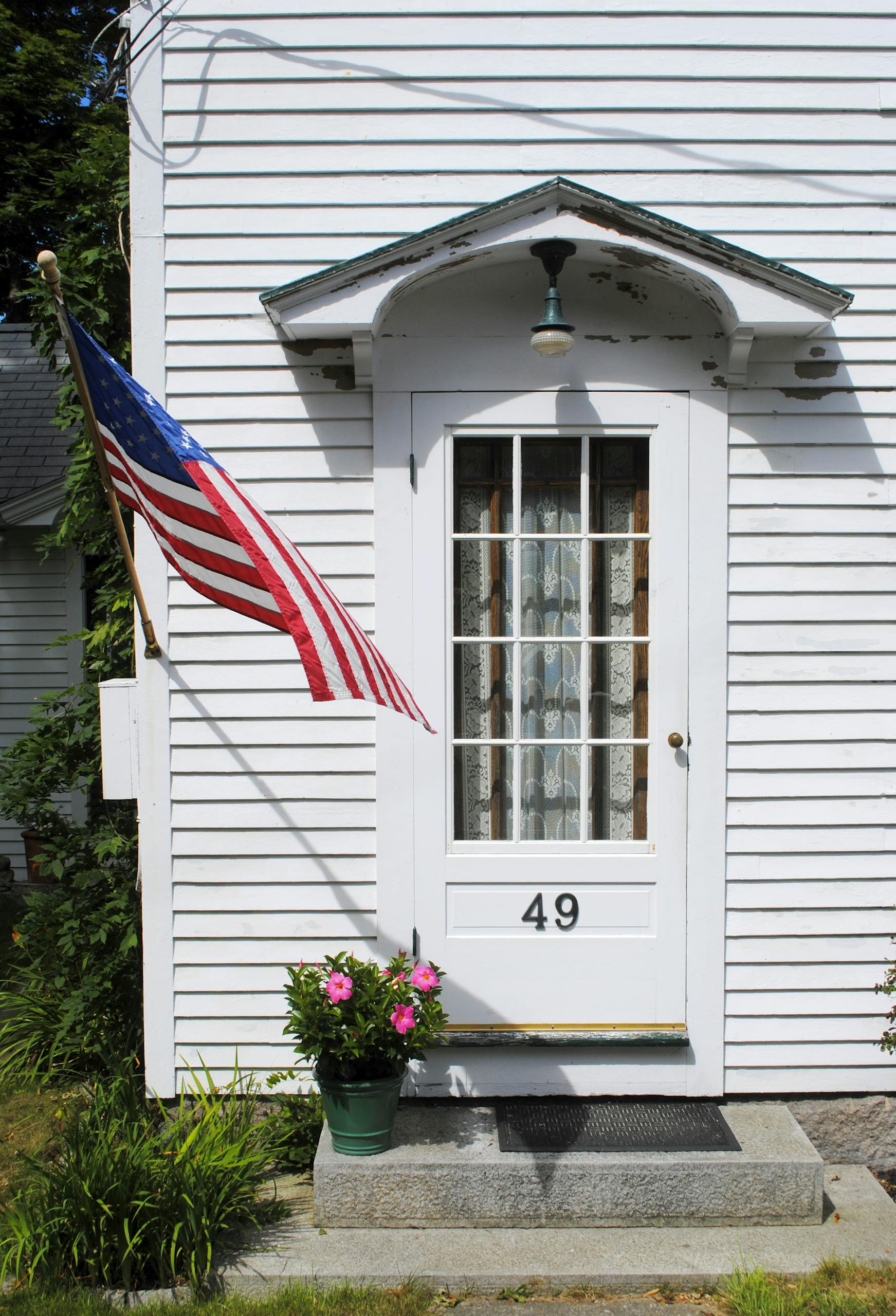 An inviting American home entrance with a patriotic flag and garden decor.